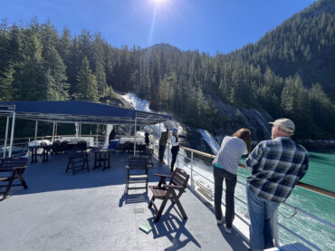 View from the Alaskan Dream top deck. Guests viewing waterfalls up close.